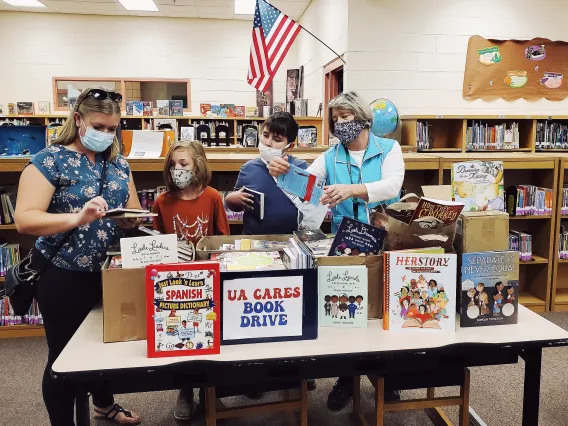 UA Cares Ambassador, Danielle Oxnam delivers books to a local elementary after hosting a book drive in her department.